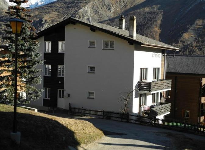 duży biały budynek z górą w tle w obiekcie Chalet Wanda w mieście Saas-Fee