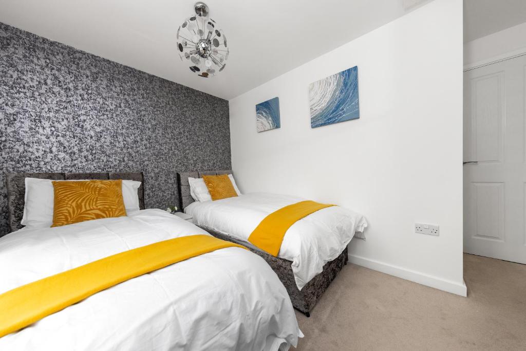 a bedroom with two beds and a chandelier at Royal House Wolverhampton - Perfect for Contractors & Large Groups in Wolverhampton