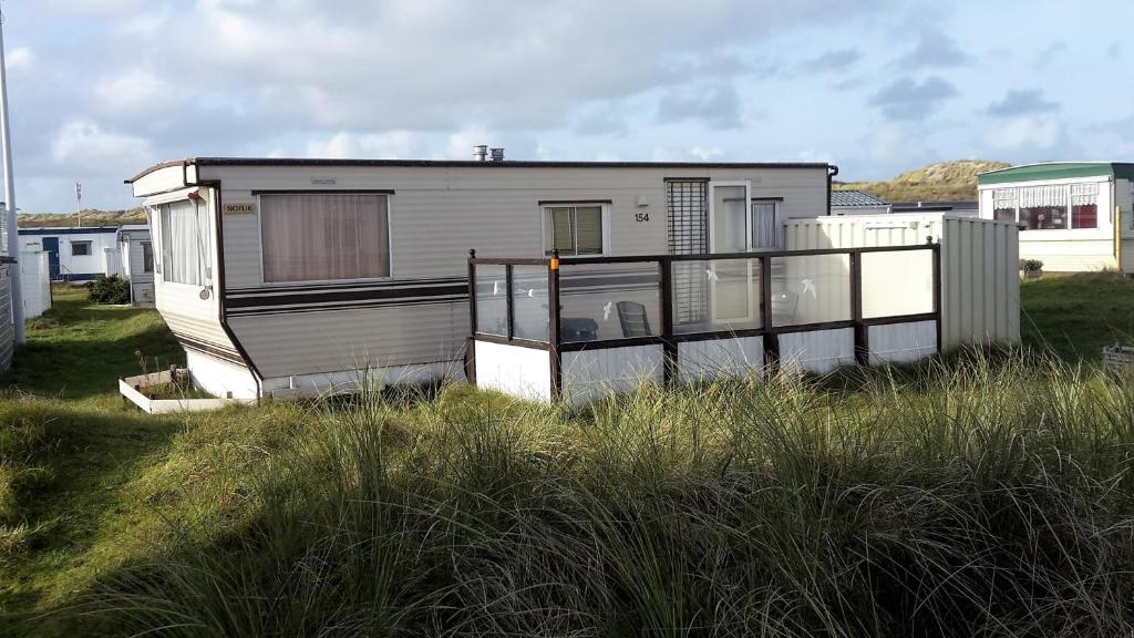 ネスにあるAMELAND-Nes-Duinoord: Stacaravan (chalet) + fietsen direct aan zee!のビーチ沿いのバルコニー付きのモバイルホームです。