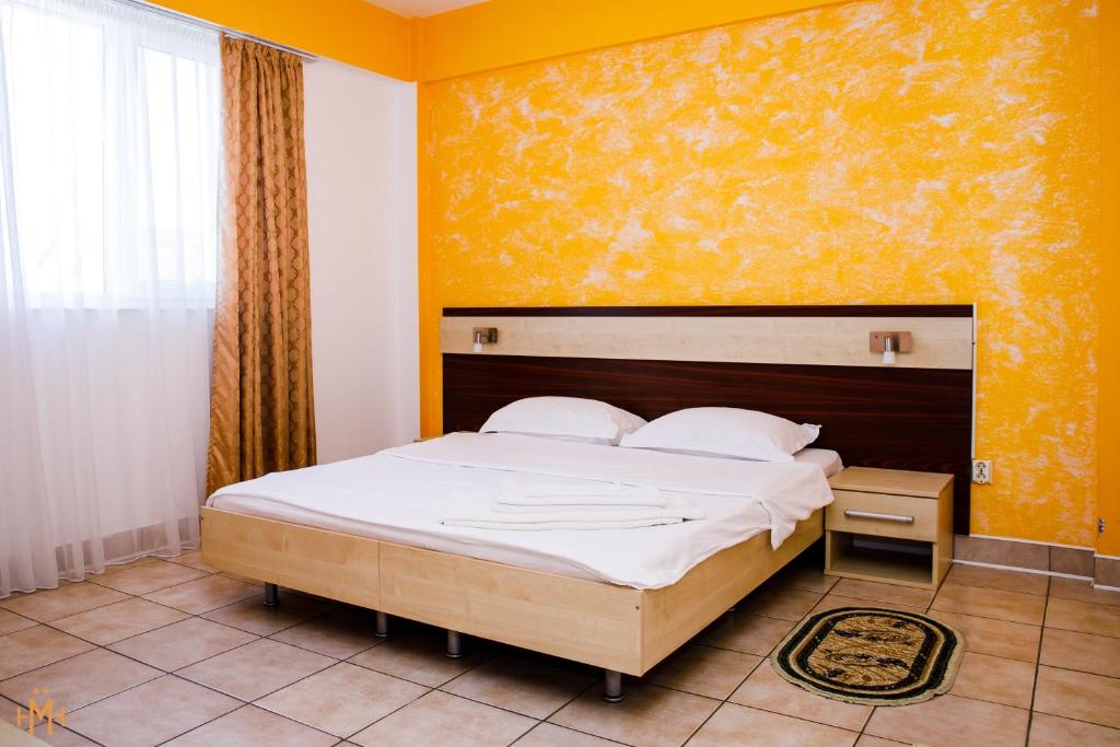 1 dormitorio con cama y pared amarilla en Hotel Meridian, en Costinesti