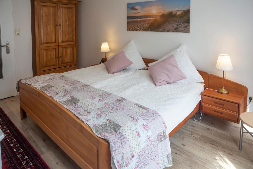 a bedroom with a bed with white sheets and pink pillows at Ferienwohnung Alt Einbeck in Einbeck