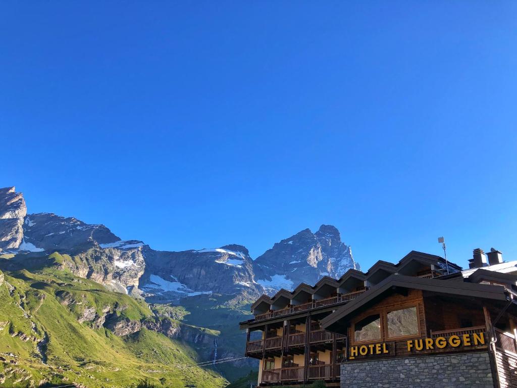 a hotel with mountains in the background at Hotel Meublé Furggen in Breuil-Cervinia