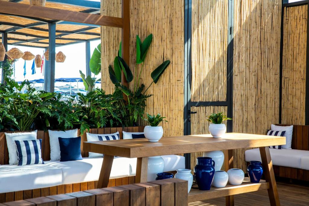 a table and benches in a room with plants at Kaya Palazzo Resort & Residences Le Chic Bodrum in Bodrum City