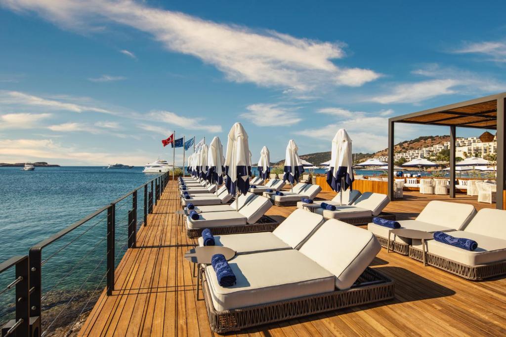 a pier with lounge chairs and umbrellas on the water at Kaya Palazzo Resort & Residences Le Chic Bodrum in Bodrum City