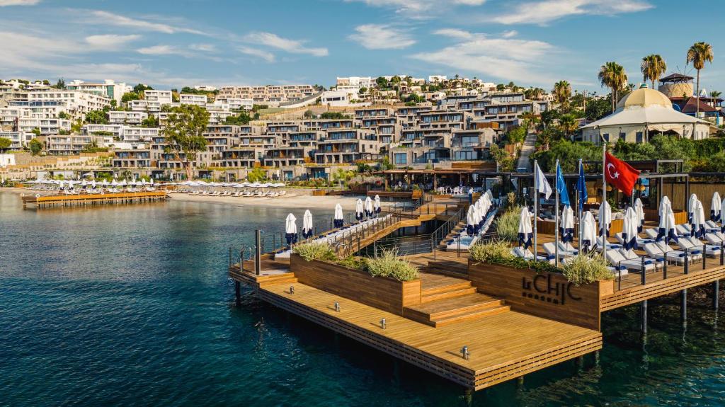 a dock with chairs and umbrellas on the water at Kaya Palazzo Resort & Residences Le Chic Bodrum in Bodrum City