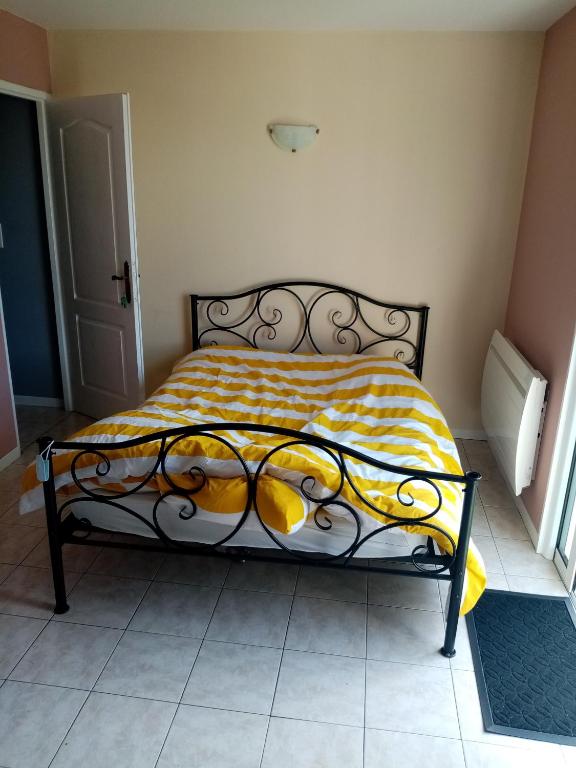 Una cama en una habitación con una manta amarilla. en Chez patou, en Jezainville