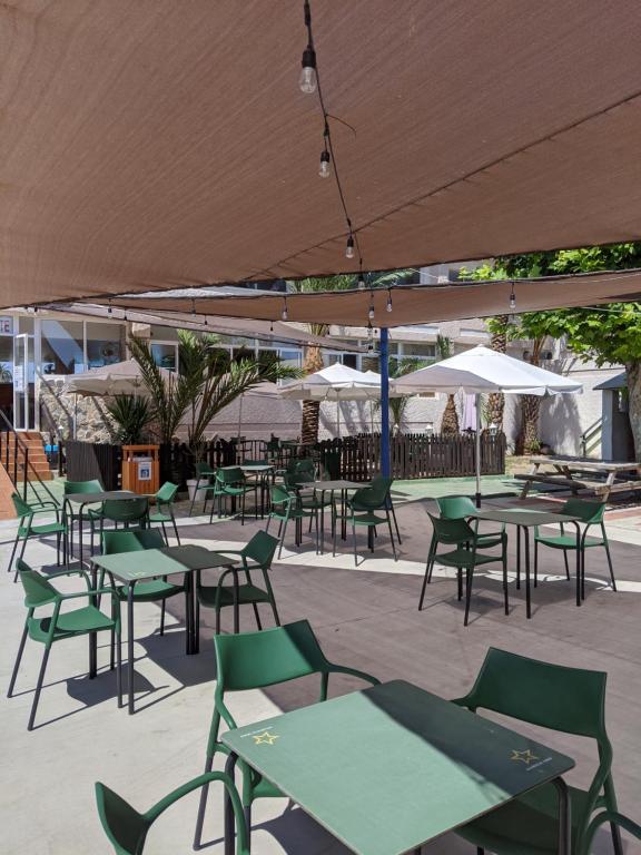 Un patio al aire libre con mesas, sillas y sombrillas. en Camping San Javier, en San Javier