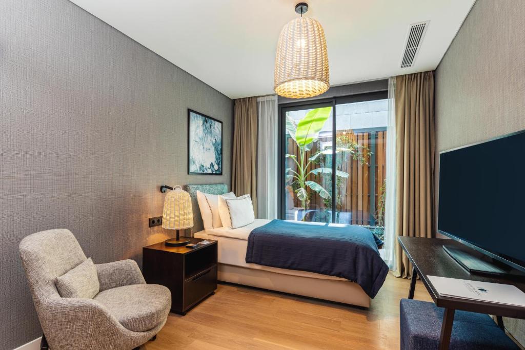 a bedroom with a bed and a desk and a tv at Kaya Palazzo Resort & Residences Le Chic Bodrum in Bodrum City