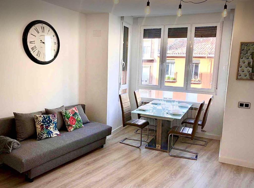 un soggiorno con divano, tavolo e orologio. di Apartamento Vive Zaragoza II a Saragozza