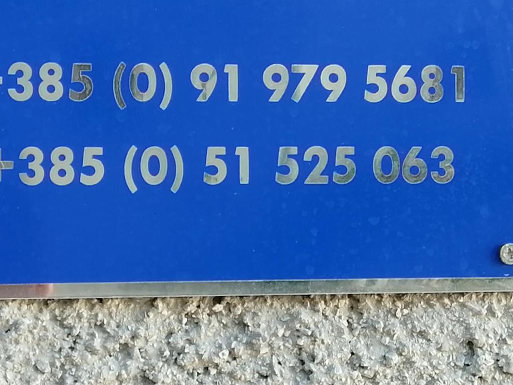 un panneau bleu avec des chiffres à côté d'un mur dans l'établissement Apartments Nevija, à Valun