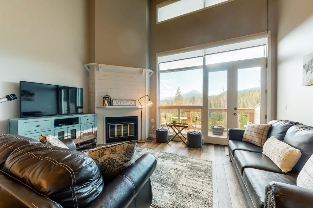 a living room with a leather couch and a fireplace at Watch Hill Lofted in Silverthorne