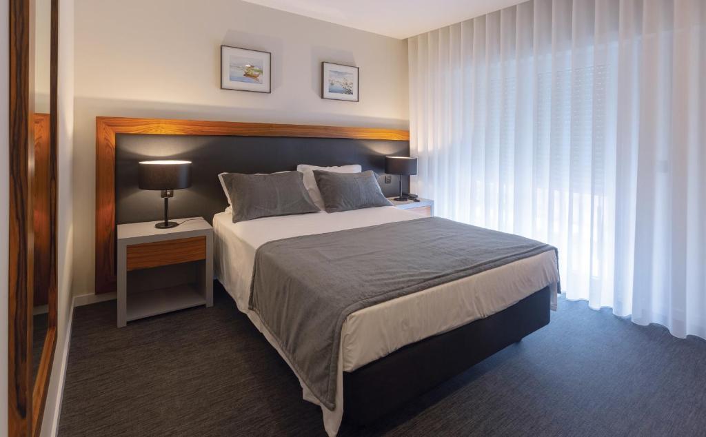 a bedroom with a large bed and a night stand with a lamp at Hotel Afonso V & SPA in Aveiro