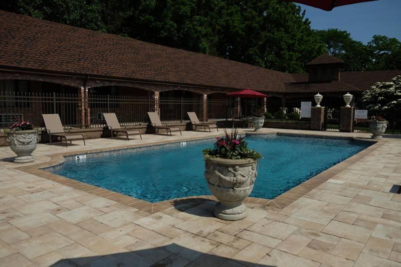 a swimming pool with chairs and a patio with at Chalet Inn & Suites in Centerport