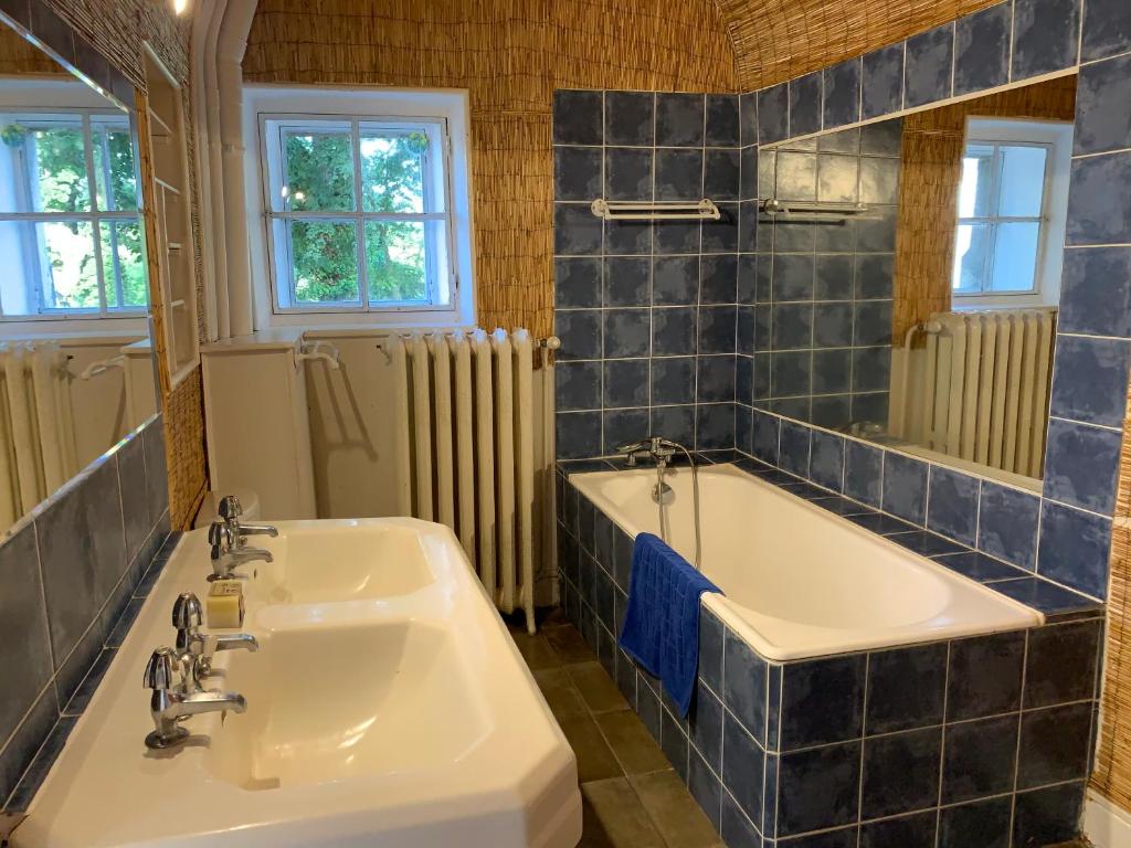 a bathroom with two sinks and a tub and a mirror at Château de Saint-Agoulin in Saint-Agoulin