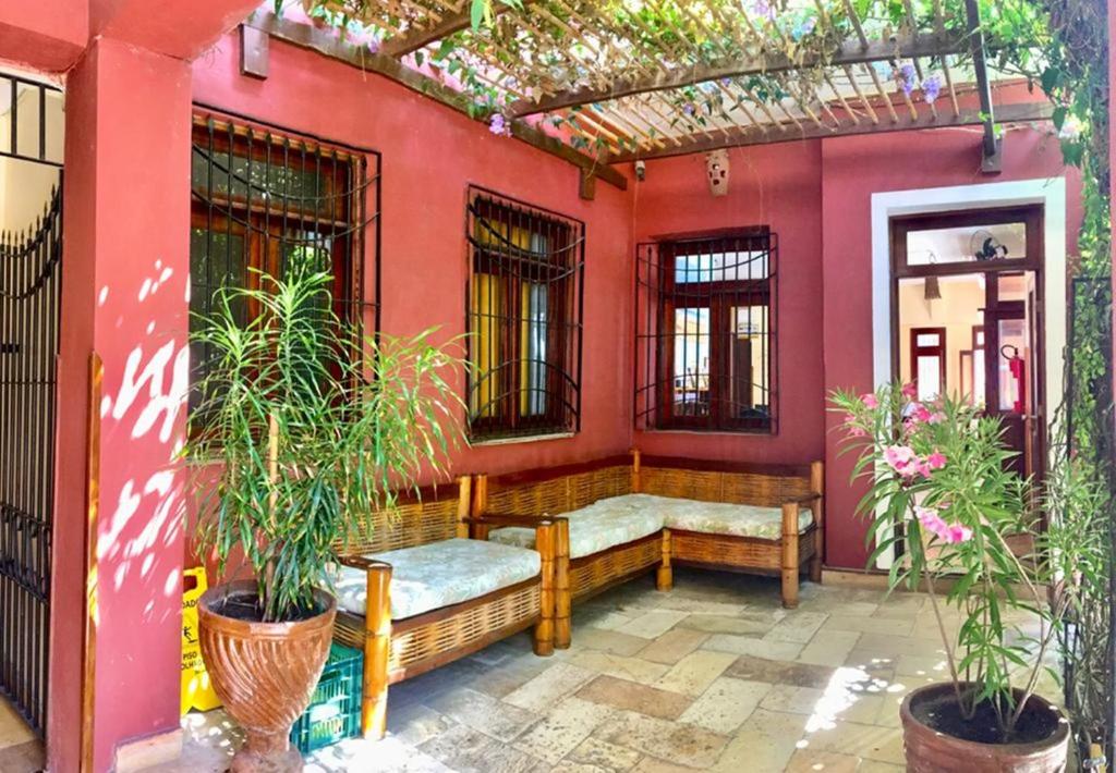 a porch with a bench and a red wall at Pousada Fortal Villa Praia in Fortaleza