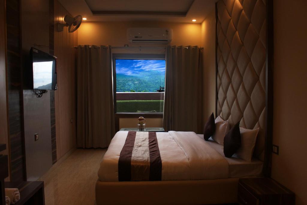 Hotel Ganga Heights في حاريدوار: غرفة نوم بسرير كبير ونافذة