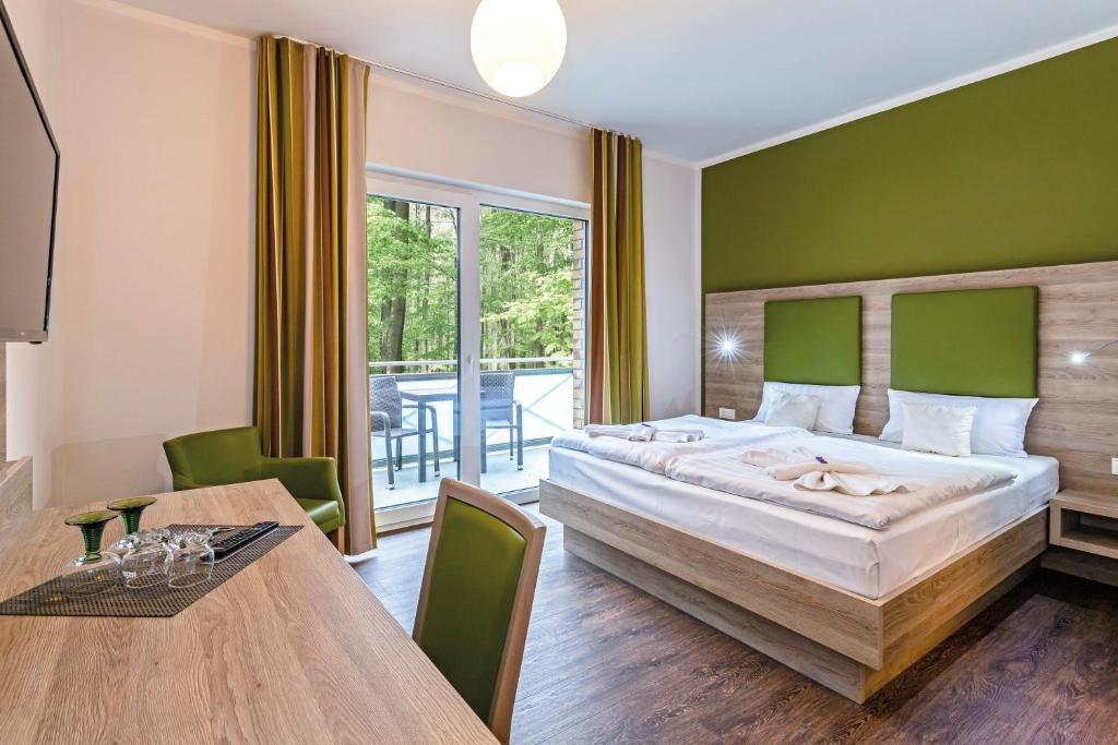 ein Schlafzimmer mit einem großen Bett und einem Esstisch in der Unterkunft Hotel zur Ostsee in Graal-Müritz