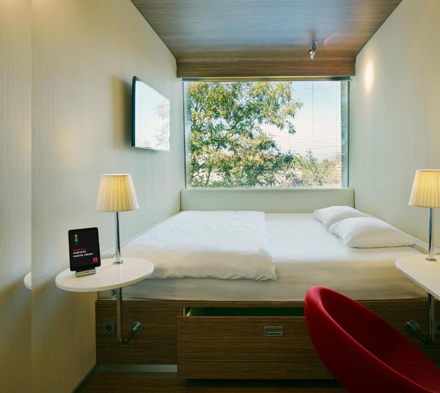 - une chambre avec un lit, deux tables et une fenêtre dans l'établissement citizenM Amsterdam South, à Amsterdam