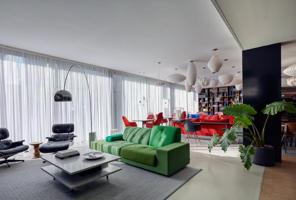a living room with a green couch and chairs at citizenM Amsterdam South in Amsterdam