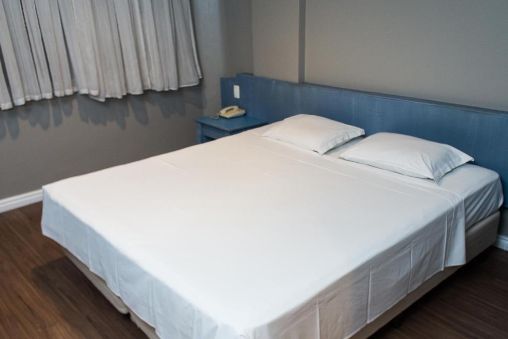 ein großes weißes Bett mit blauem Kopfteil in einem Zimmer in der Unterkunft Master Express Alberto Bins - 200 metros do Hospital Santa Casa in Porto Alegre