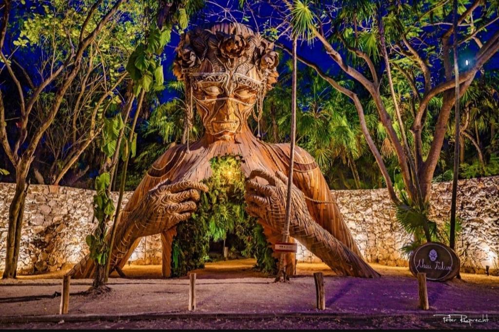 una estatua de un hombre sosteniendo una planta en Ahau Tulum, en Tulum