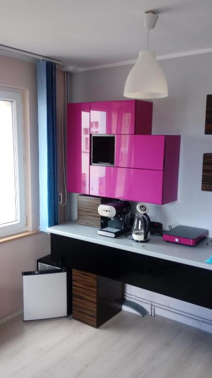 Zimmer mit einem Schreibtisch und einer rosa Wand in der Unterkunft Apartament Puck in Puck