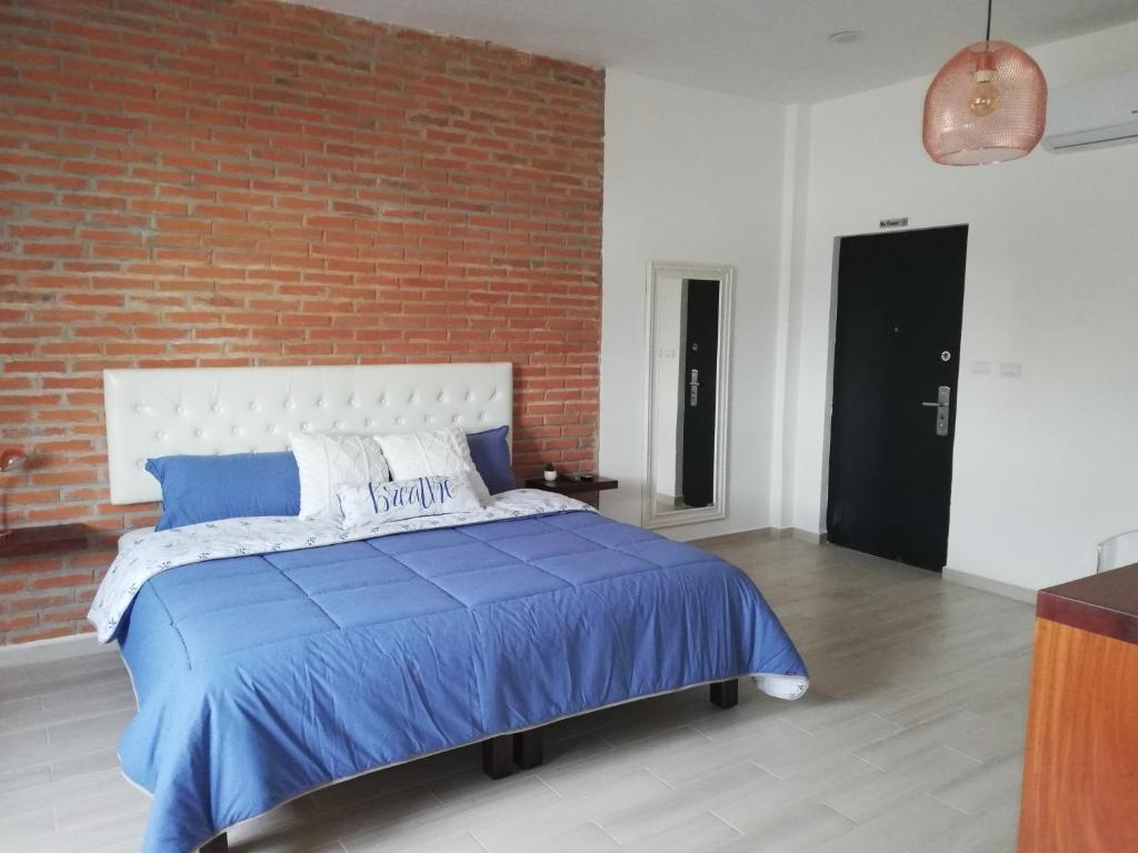 a bedroom with a large bed with a brick wall at La Maja Suites in Villahermosa