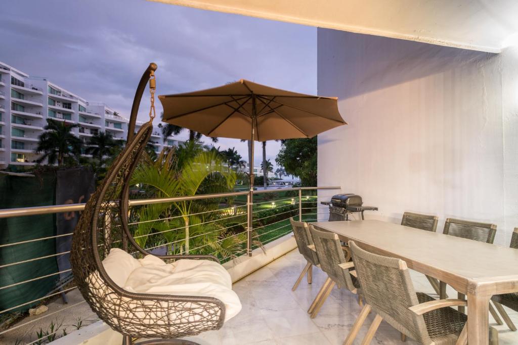a hammock on a balcony with a table and an umbrella at RESTYLE: Ocean front + pool Nuevo Vallarta in Nuevo Vallarta 