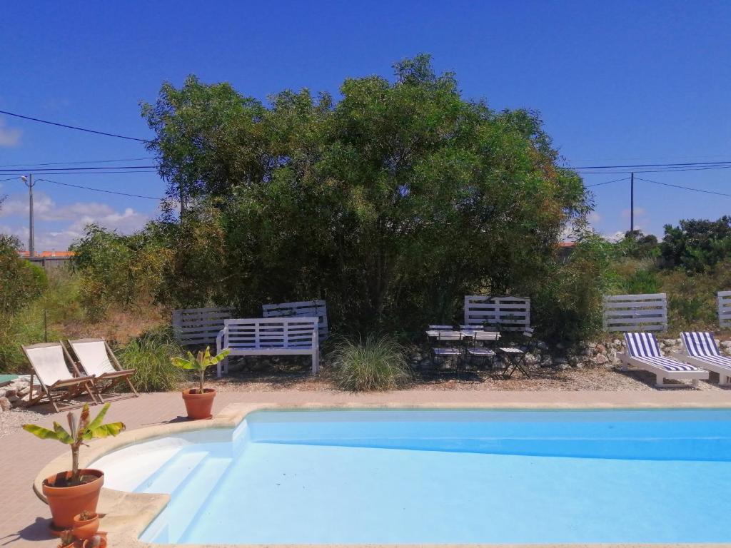 a swimming pool with two chairs and a tree at Endless Summer Surf House in Aljezur