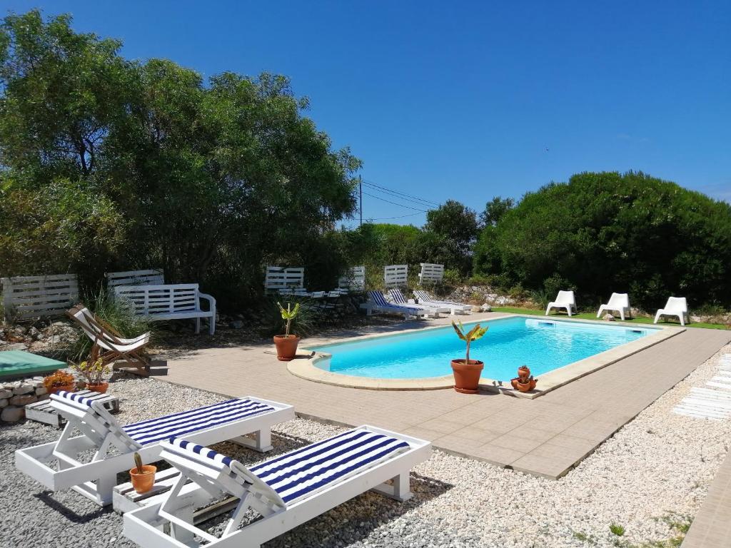 a swimming pool with two lounge chairs and a table at Endless Summer Surf House in Aljezur