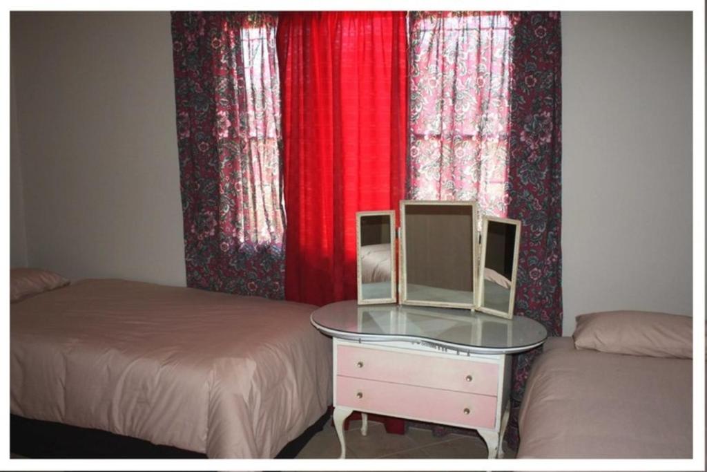 a bedroom with two beds and a table with a mirror at Confortable farmhouse in Limpopo Province in Lephalale