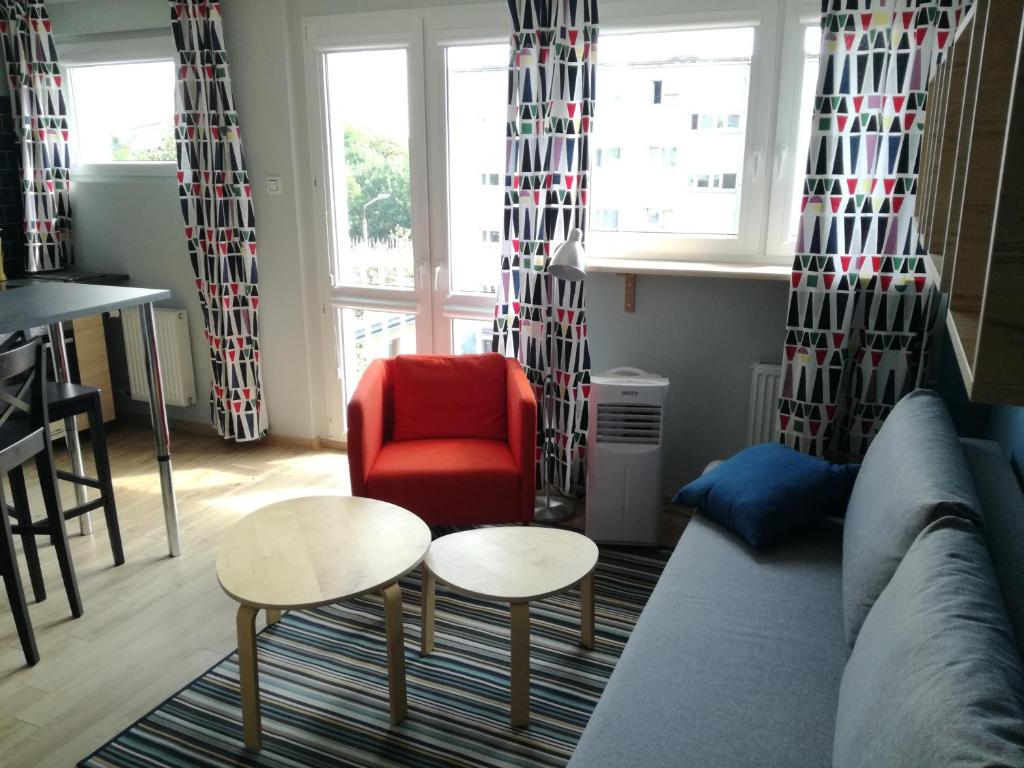 uma sala de estar com um sofá e uma cadeira vermelha em Wrocław - nowoczesne mieszkanie w pełni wyposażone em Breslávia