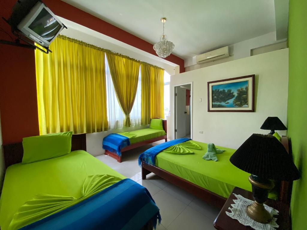 1 dormitorio con 2 camas y una ventana con cortinas amarillas en Hostal Puerto Azul, en Manta
