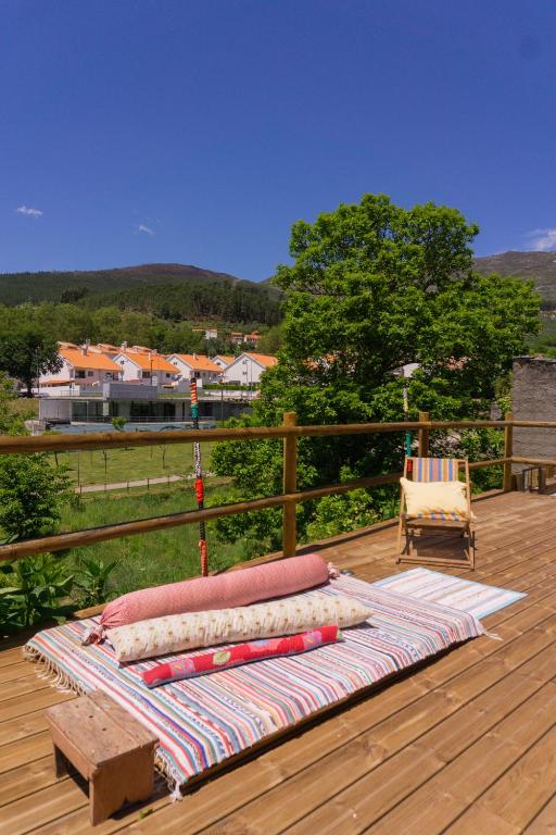 1 cama en una terraza de madera con silla en Casa da Almoinha, en Unhais da Serra