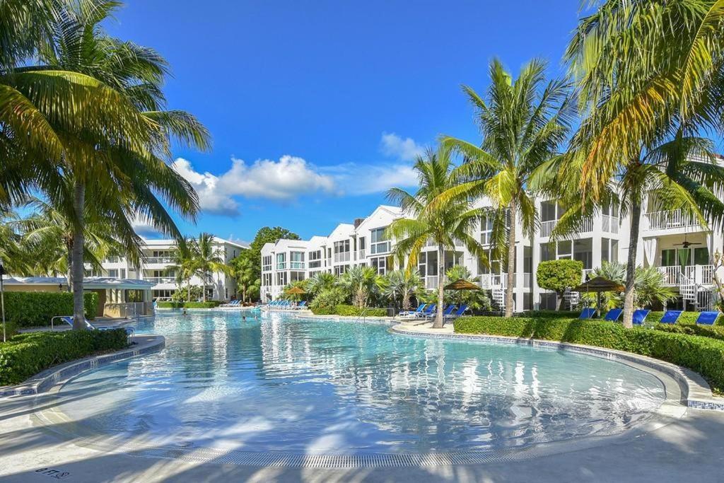 una piscina con palmeras frente a un complejo en LICENSED MGR - 3/3.5 MODERN VILLA - KEY LARGO'S PREMIER OCEANFRONT RESORT AND MARINA! en Key Largo