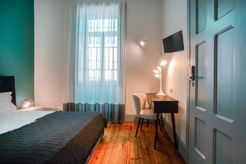 Un dormitorio con una cama y un escritorio y una ventana. en Palacete Suite Aveiro, en Aveiro