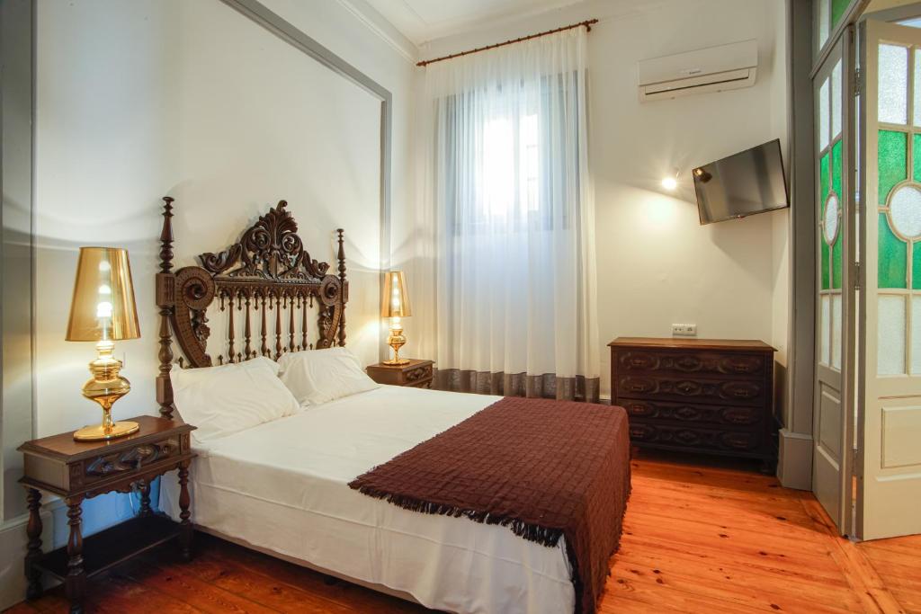 a bedroom with a large bed and a television at Palacete Suite Aveiro in Aveiro