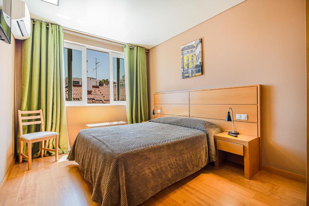 a hotel room with a bed and a window at Hotel Botanico in Lisbon