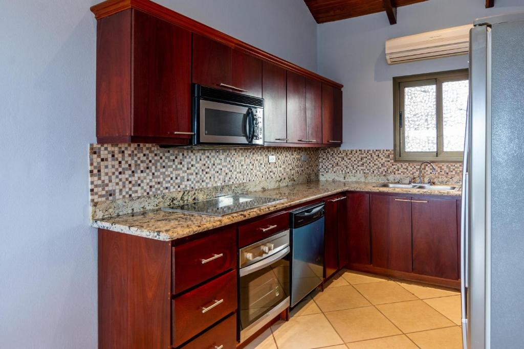 uma cozinha com armários de madeira e um micro-ondas em 1-Bedroom Ocean-View Condo with Pool em Playa Flamingo