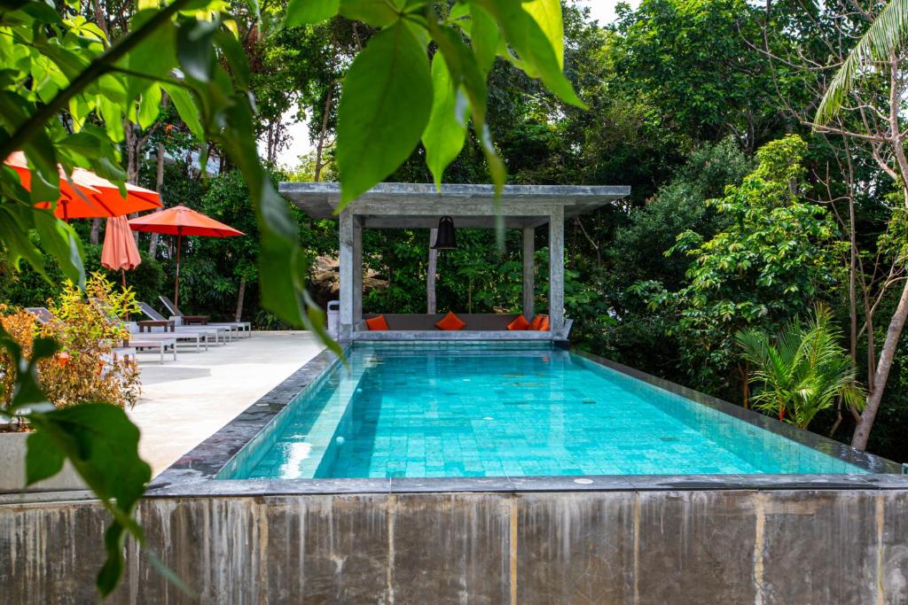 a swimming pool with a table and an umbrella at Padel Phangan Suite in Chaloklum