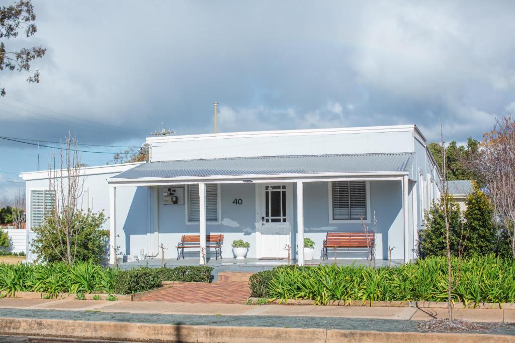 a blue and white house with two benches at The Rested Guest 3 Bedroom Cottage West Wyalong in West Wyalong