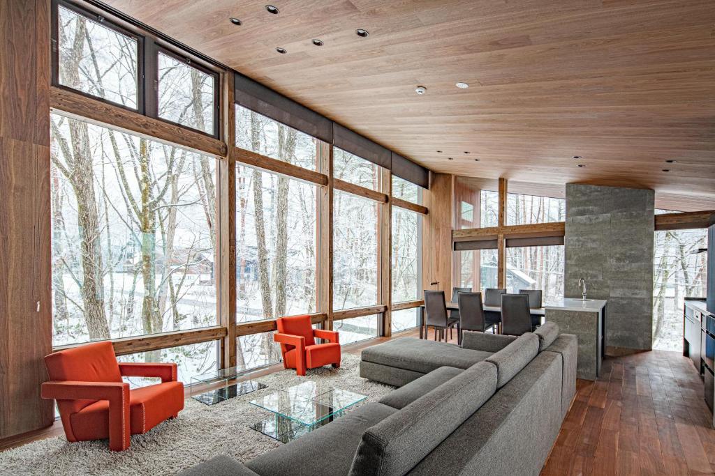 a living room with a couch and chairs and windows at Gravity by The Hakuba Collection in Hakuba