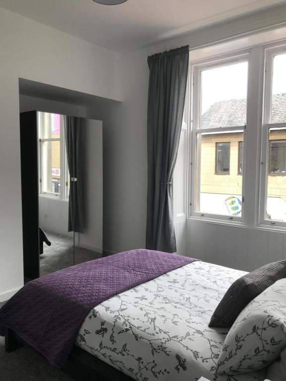 a bedroom with a bed and two windows at Carvetii - Edward House A - 2 Dbl bed 1st floor flat in Dunfermline