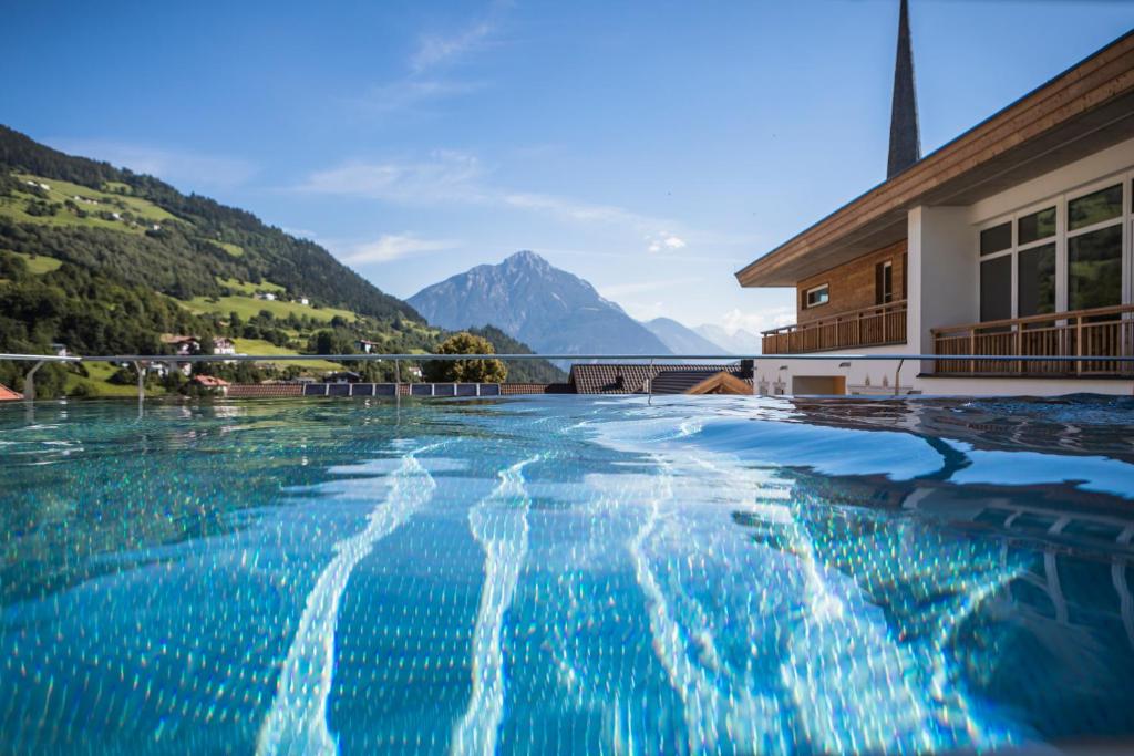 a swimming pool with a mountain in the background at Kinderhotel Stefan in Wenns