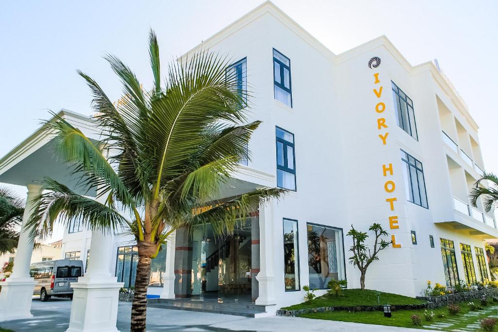 a palm tree in front of a white building at Ivory Phu Yen Hotel in Tuy Hoa