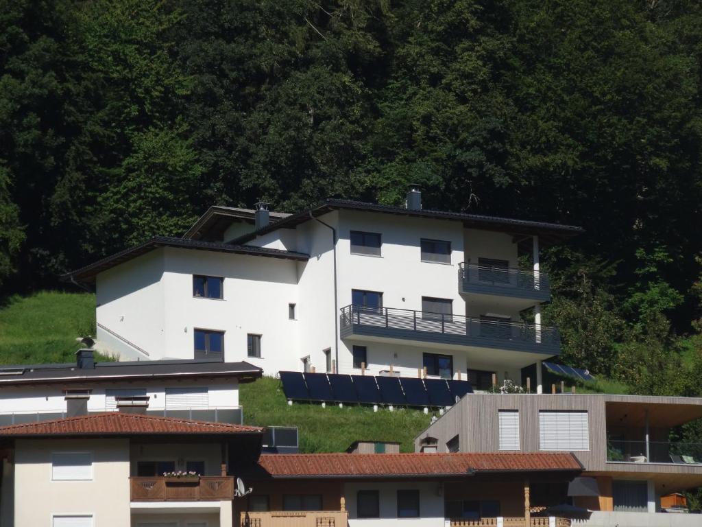 ein weißes Gebäude auf einem Hügel mit Bäumen in der Unterkunft Panorama Apartment in Bruck am Ziller