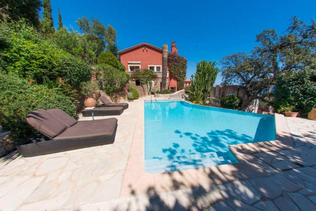 a swimming pool with two lounge chairs next to a house at Villa lours in Le Trayas