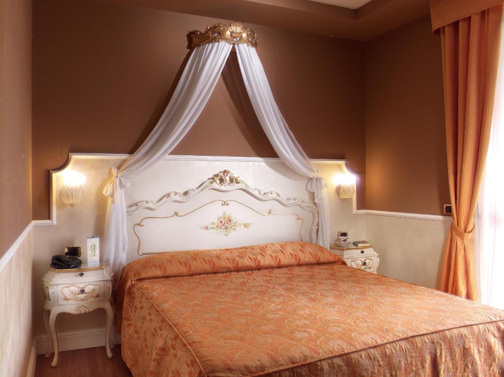 a bedroom with a large bed with a canopy at Hotel Confine in Colà di Lazise