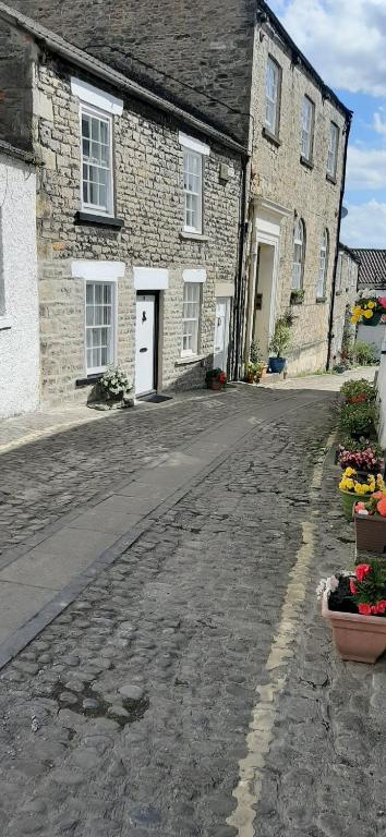 an empty street in front of a stone house at 16th Century 1 Bedroom Cottage (adjacent 10th Century Richmond Castle) in Richmond