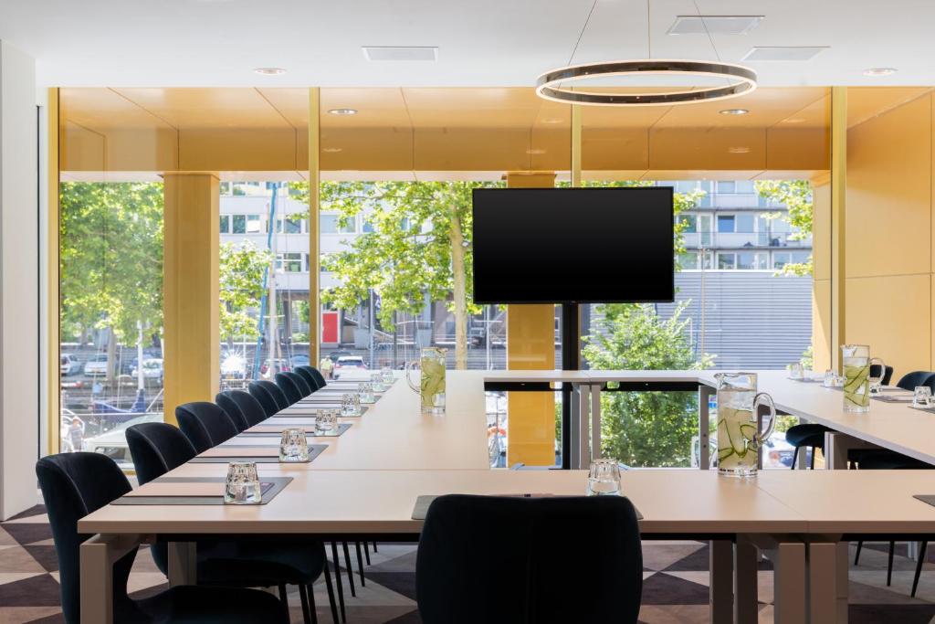 a large conference room with tables and chairs and a flat screen tv at Holiday Inn Express Amsterdam - North Riverside by IHG in Amsterdam